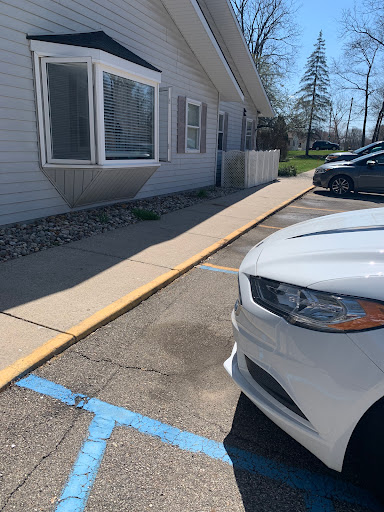A white car parked in a lot next to a building with a sidewalk.