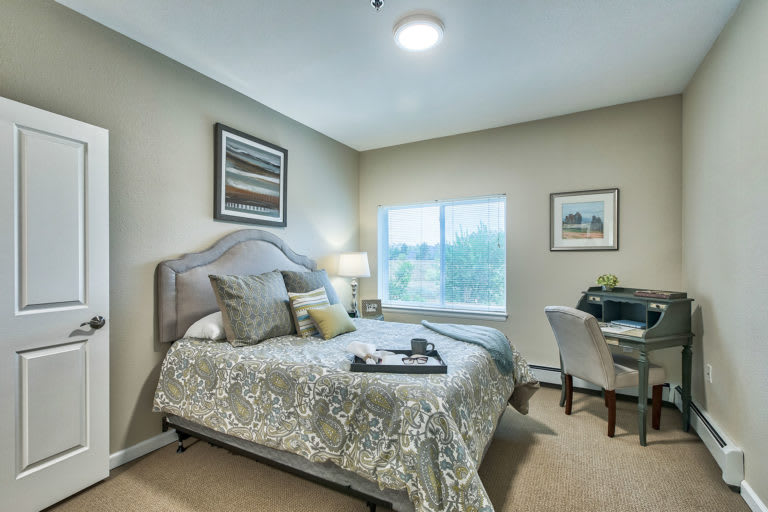 A cozy and well-decorated bedroom featuring a neatly made bed, a desk with a chair, and soft lighting.