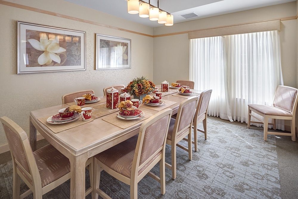 A well-decorated dining room with a table set for a meal, featuring elegant decor and ample natural light.