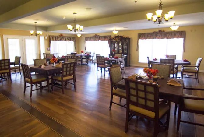 A spacious dining area with wooden flooring and elegant chandeliers.