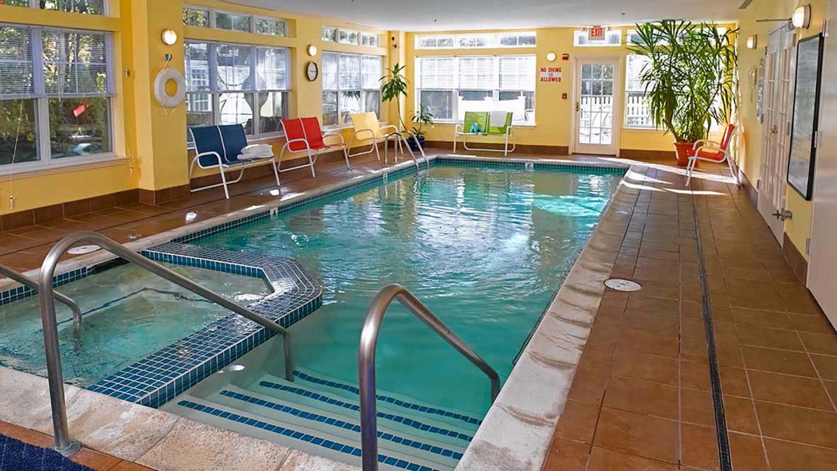 A bright indoor swimming pool area with chairs and plants, providing a relaxing atmosphere.