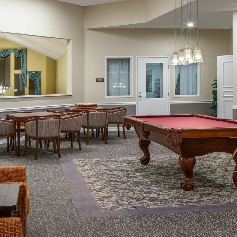 A spacious game room featuring a pool table and several seating areas.