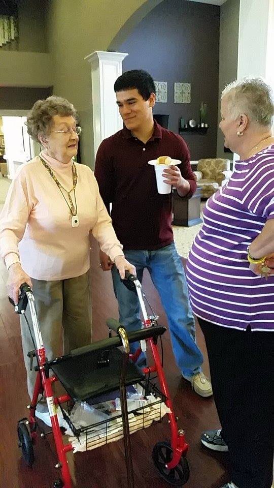A group of people having a conversation in an indoor setting, with one person using a walker.