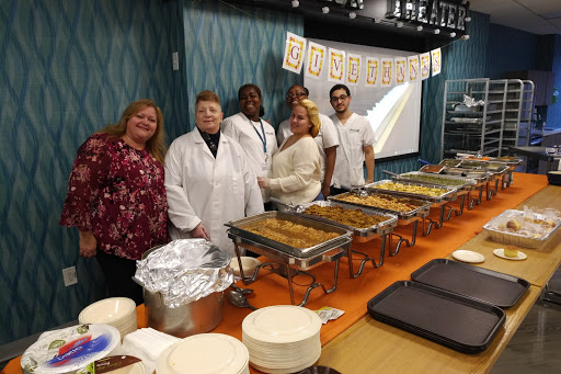 A team of dedicated individuals poses together behind a buffet setup, showcasing a variety of delicious dishes.