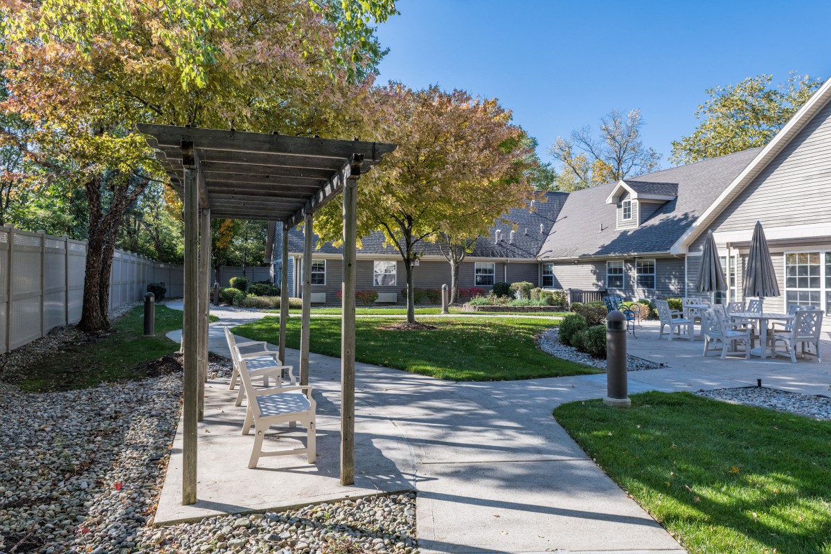 A peaceful garden setting with a pathway, benches, and surrounding trees.