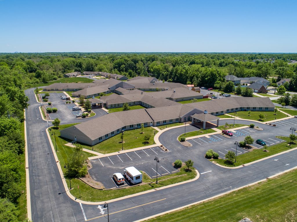 Aerial view of a large building complex surrounded by greenery and parking lots.