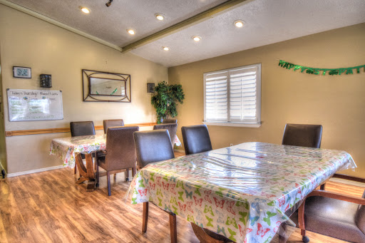 A cozy and well-lit dining room featuring tables with colorful tablecloths and comfortable chairs.