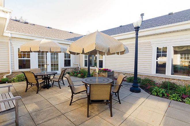 A cozy outdoor patio area with tables, chairs, and umbrellas adjacent to a building.