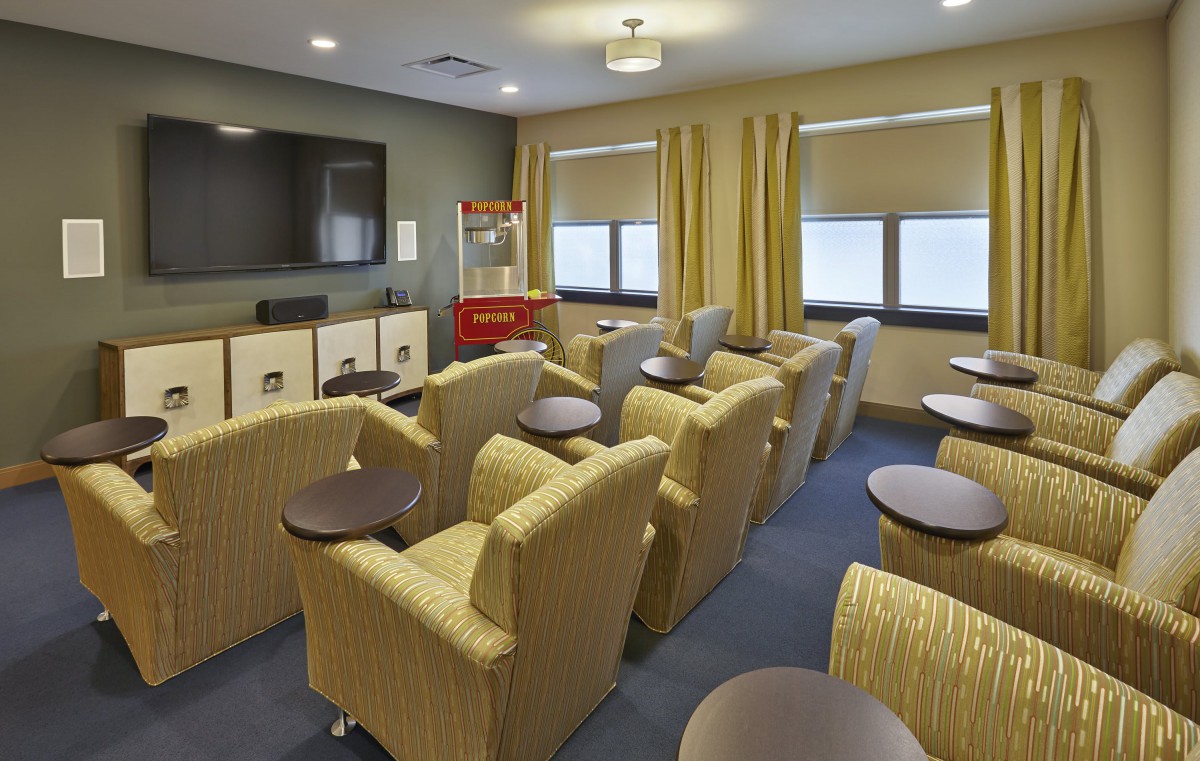 A cozy indoor movie theater room with comfortable seating and a popcorn machine.