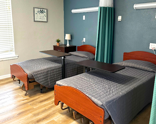A neatly arranged hospital patient room featuring multiple beds and a calm color scheme.