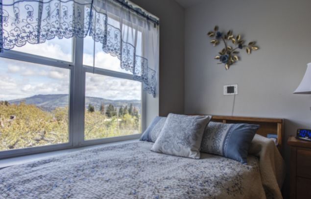 A cozy bedroom with a large window offering a scenic view and natural light.