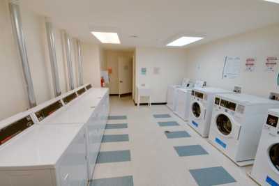 A spacious laundry room featuring multiple washing machines and dryers.