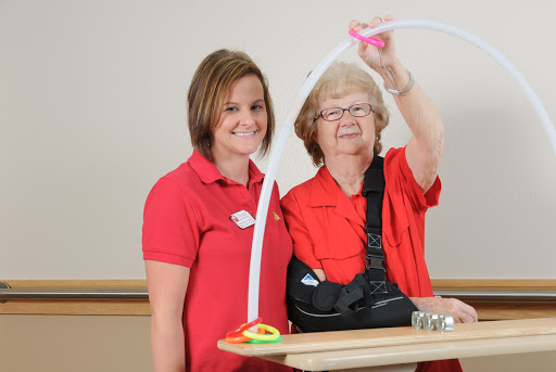 A caregiver and an elderly woman engage in a therapeutic activity, showcasing the importance of rehabilitation in healthcare.