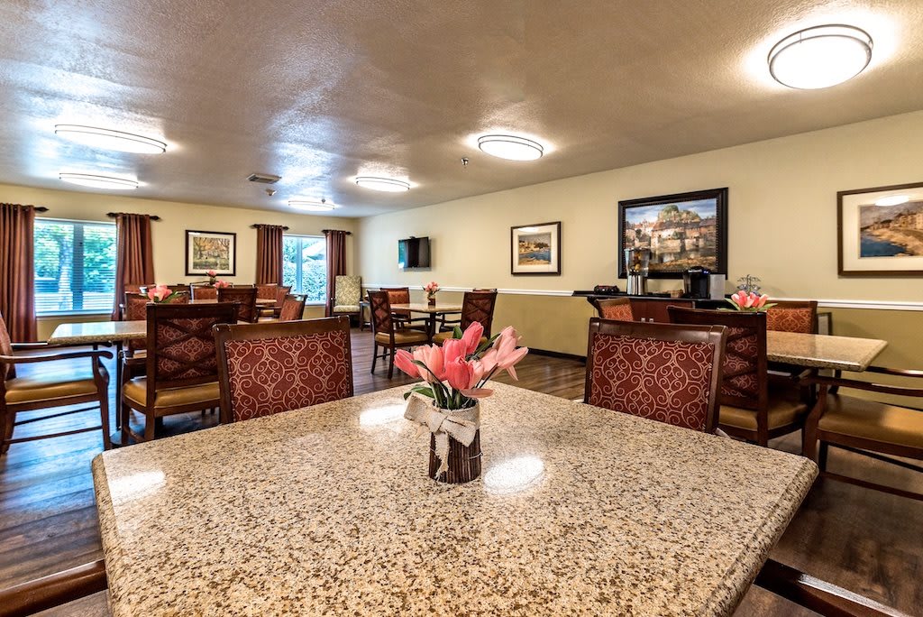 A well-lit community dining area with tables, chairs, and floral decor.