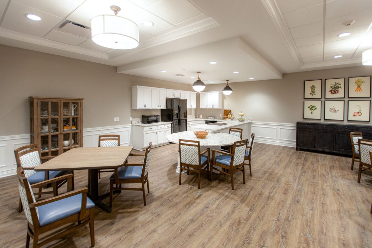 A modern kitchen and dining area featuring wood flooring, stylish lighting, and elegant furniture.