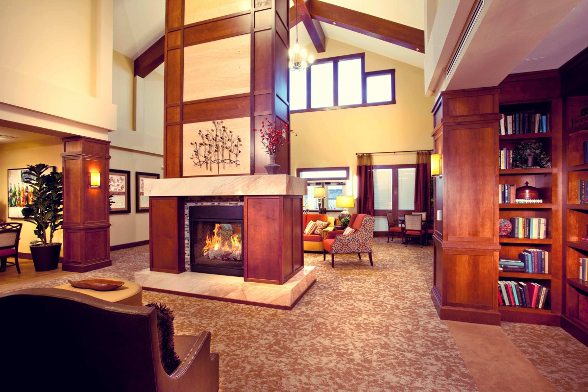 A modern and cozy living room featuring a central fireplace, elegant furniture, and large windows.