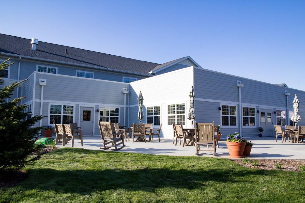 A sunny patio area with chairs and tables in front of a modern building.