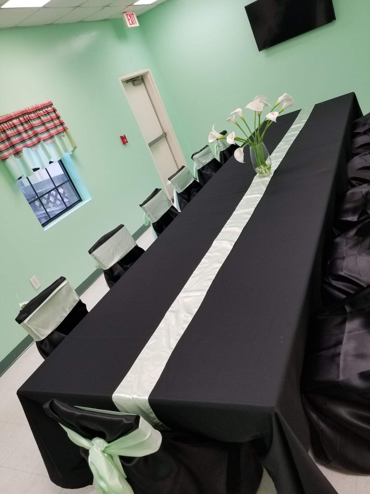 A long table set up with a black tablecloth and a decorative centerpiece, ready for an event.