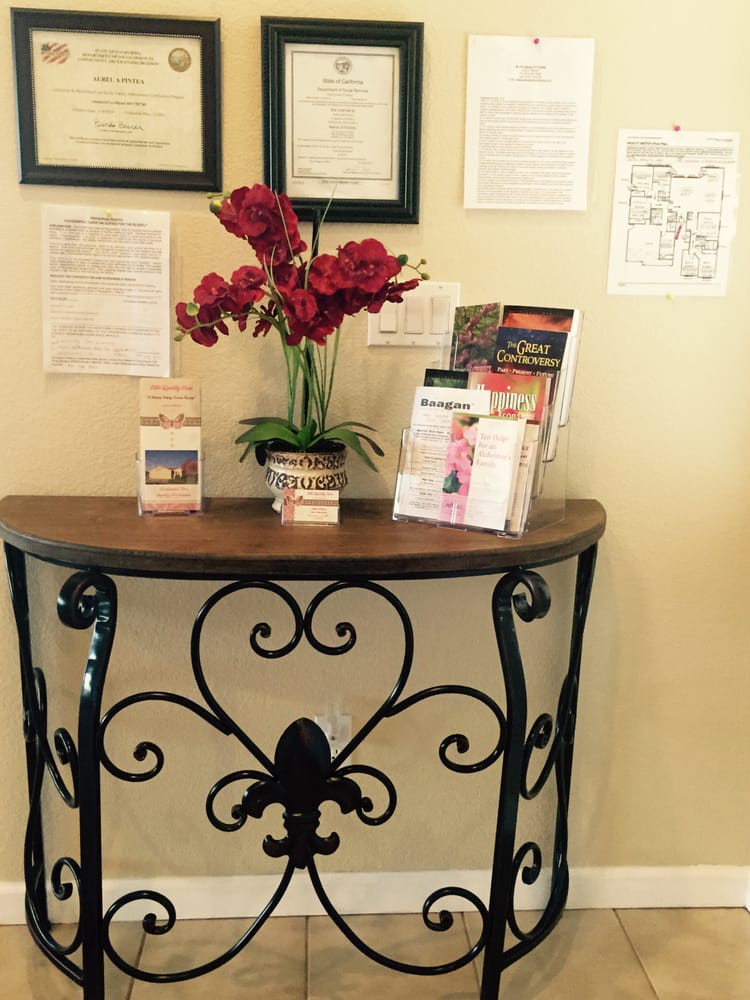 A decorative table with flowers and brochures against a wall adorned with framed certificates.