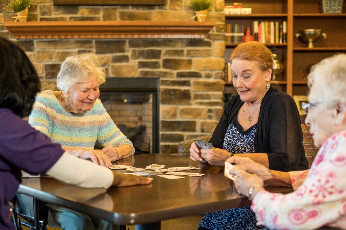 A group of elderly people enjoying a game of cards together indoors.