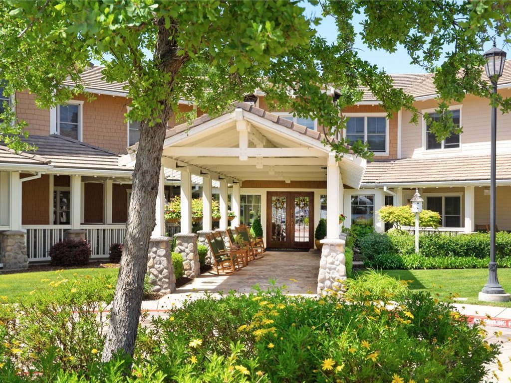 A welcoming residential building with a landscaped entrance surrounded by lush greenery.