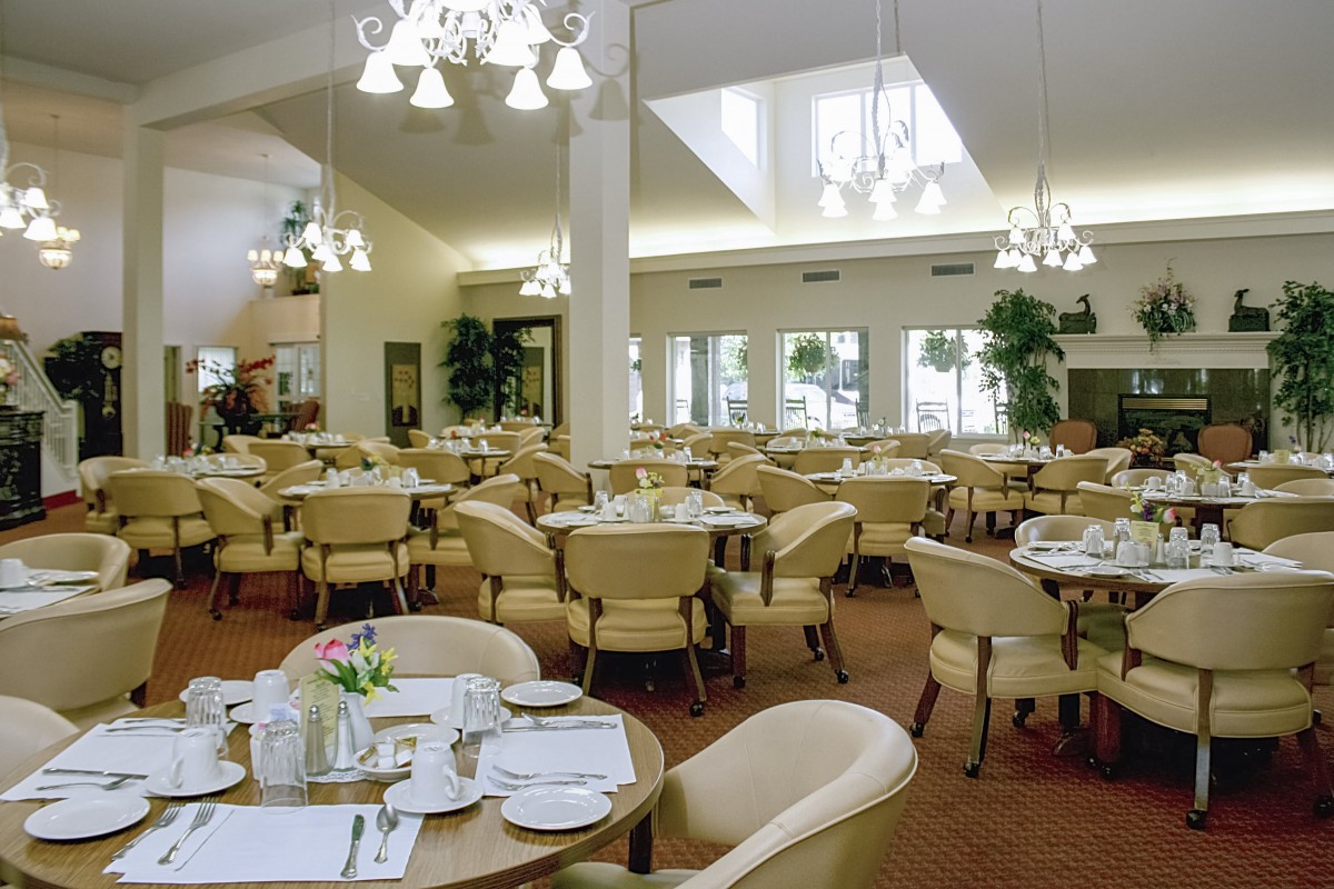 A spacious and elegantly decorated dining area with multiple round tables set for service.