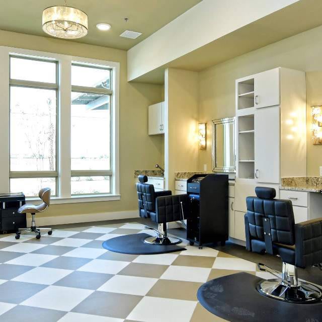 A modern and spacious salon interior with styling chairs, mirrors, and ample lighting.