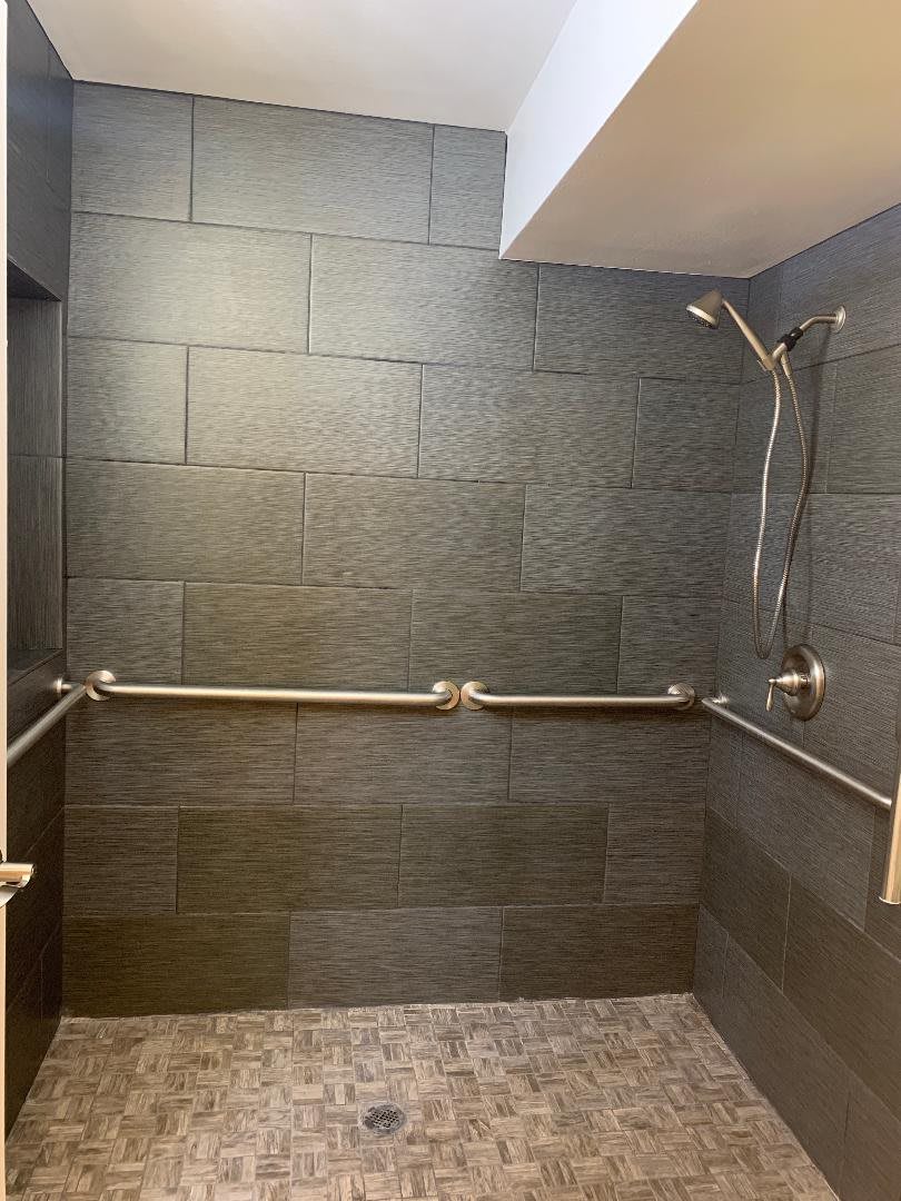 Accessible shower with grab bars and a handheld showerhead.