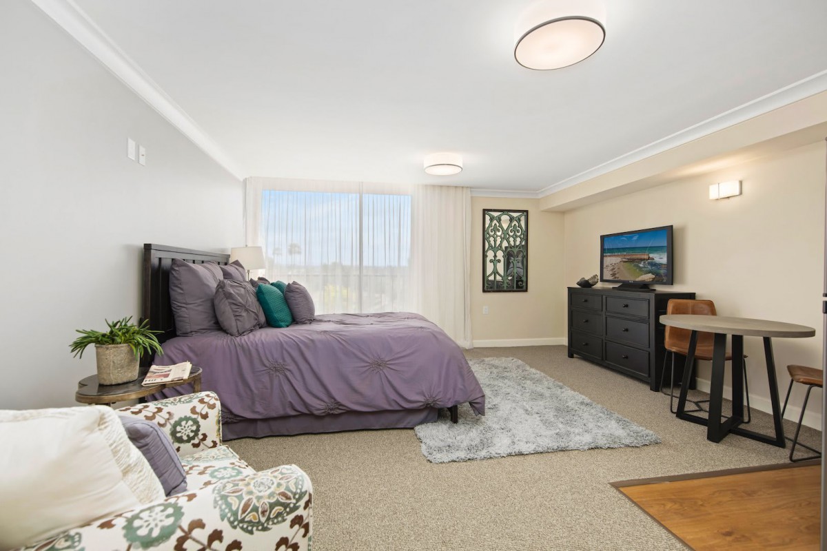A modern and cozy bedroom with a neatly made bed, stylish furniture, and a soft carpet.