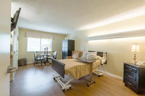 A well-lit hospital patient room featuring a bed, seating area, and window.