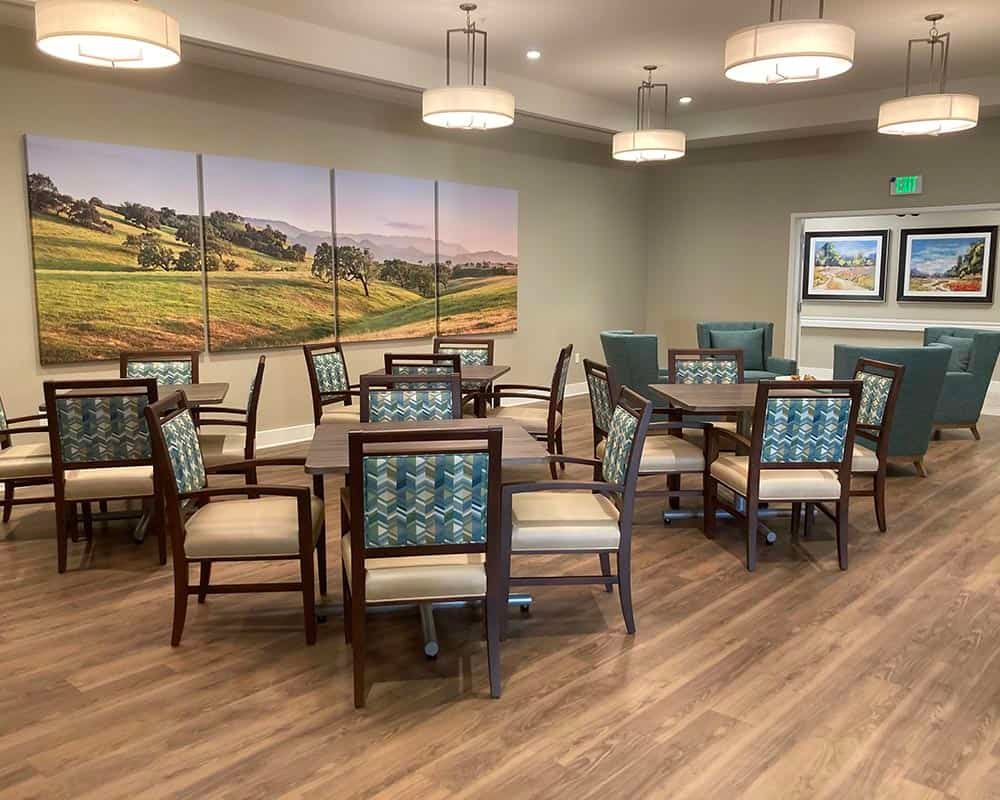 A modern dining room with neatly arranged tables and chairs, complemented by elegant lighting and wall art.