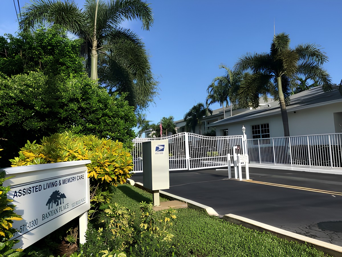 Entrance to a gated residential community with palm trees and clear skies.