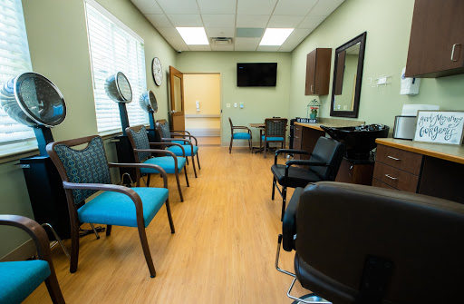A spacious waiting room in a salon, featuring modern chairs and a calm green decor.