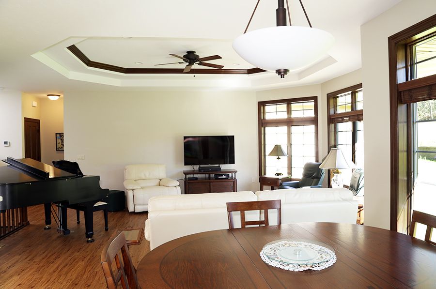 A spacious living room featuring comfortable seating, a piano, and a large television.