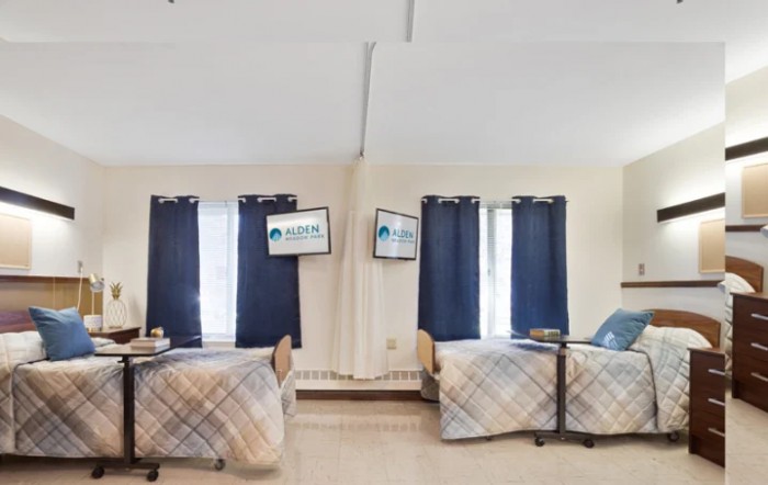 A cozy bedroom with two neatly arranged beds and blue curtains.