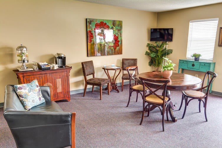 A cozy interior space featuring a seating area with a table, chairs, a wall-mounted television, and decorative artwork.
