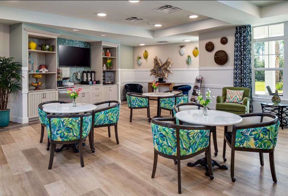 A cozy and modern dining area with colorful chairs and tables, featuring decorative elements on the walls and a television.