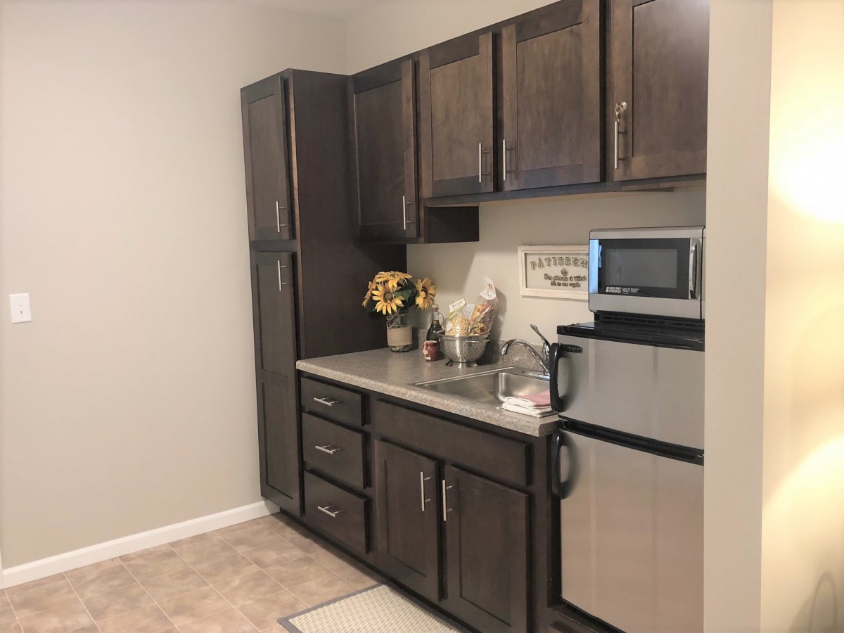 A compact and modern kitchen with dark cabinets and stainless steel appliances.