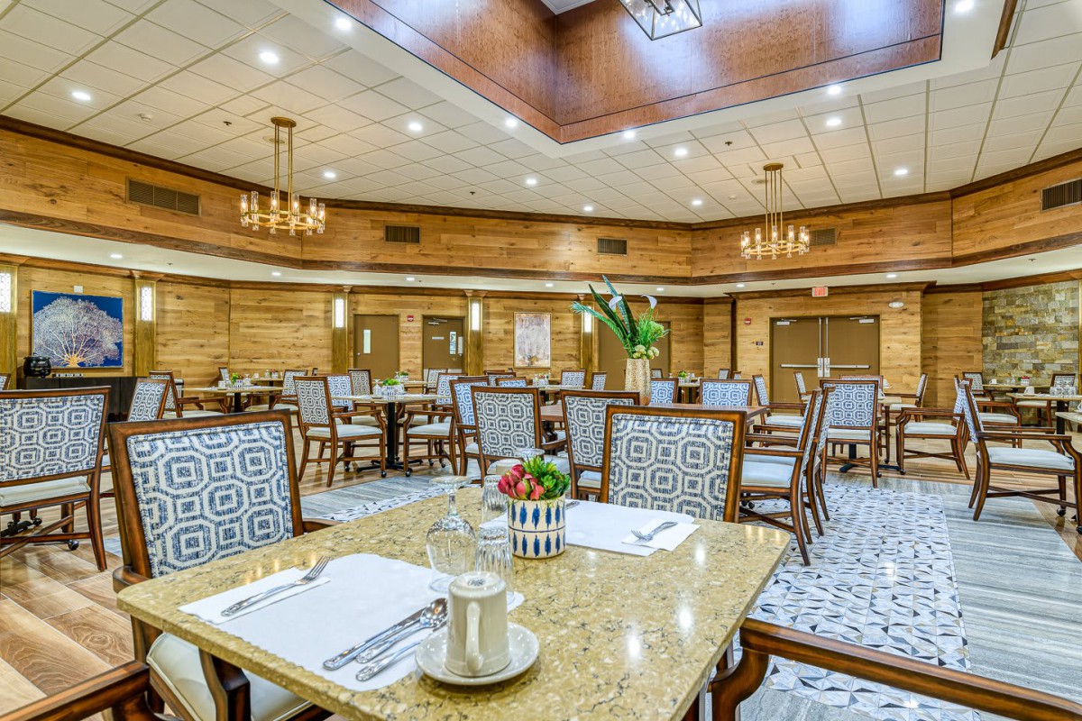 An elegant dining room with neatly arranged tables and chairs, adorned with chandeliers and tasteful decor.