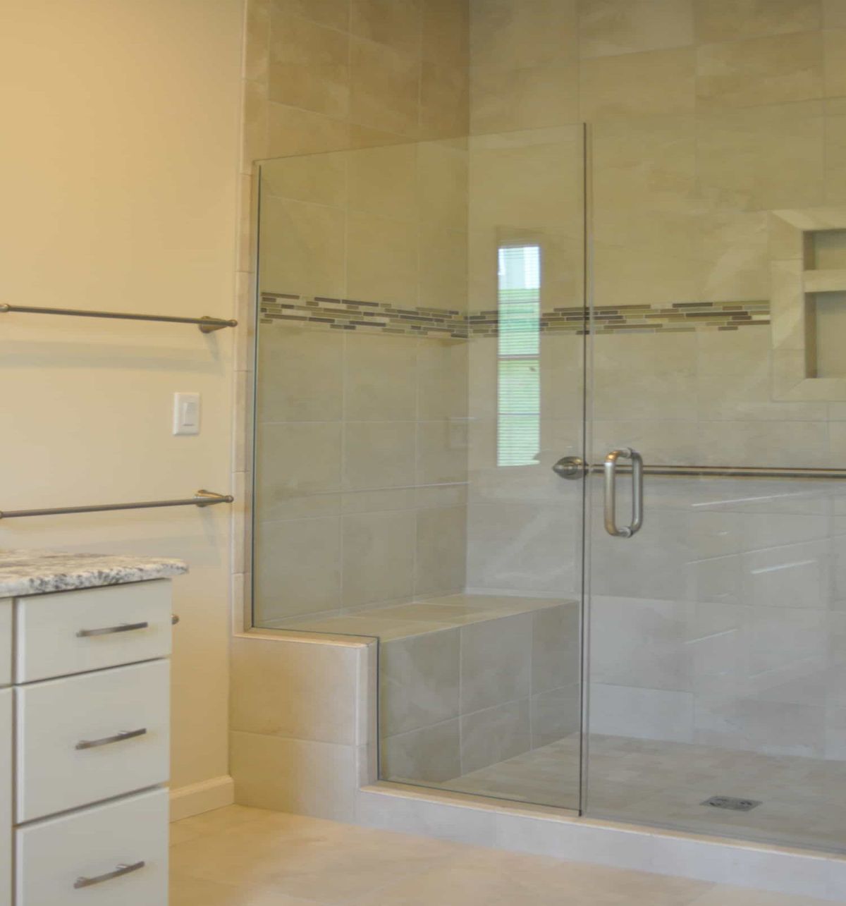 Modern bathroom with a glass-enclosed shower and tiled walls.
