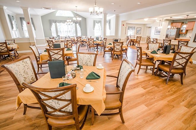 An elegantly set dining room with multiple tables and chairs, ready for guests.