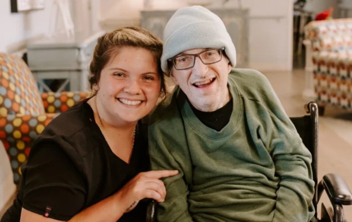 Two people smiling warmly indoors, sharing a moment of happiness and companionship.