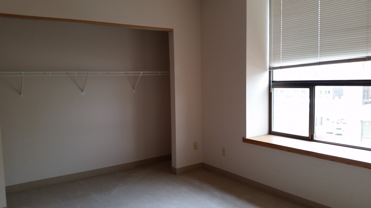 An empty room with a closet and a window, showcasing a minimalist interior.