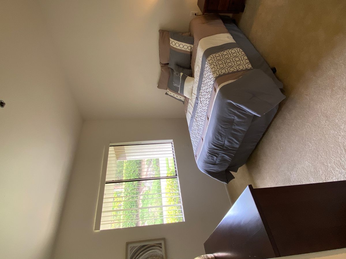 A cozy bedroom featuring a neatly made bed, a window allowing natural light, and simple decor.