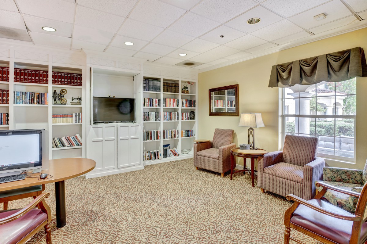 A cozy living room with a seating area, bookshelves, and a television.