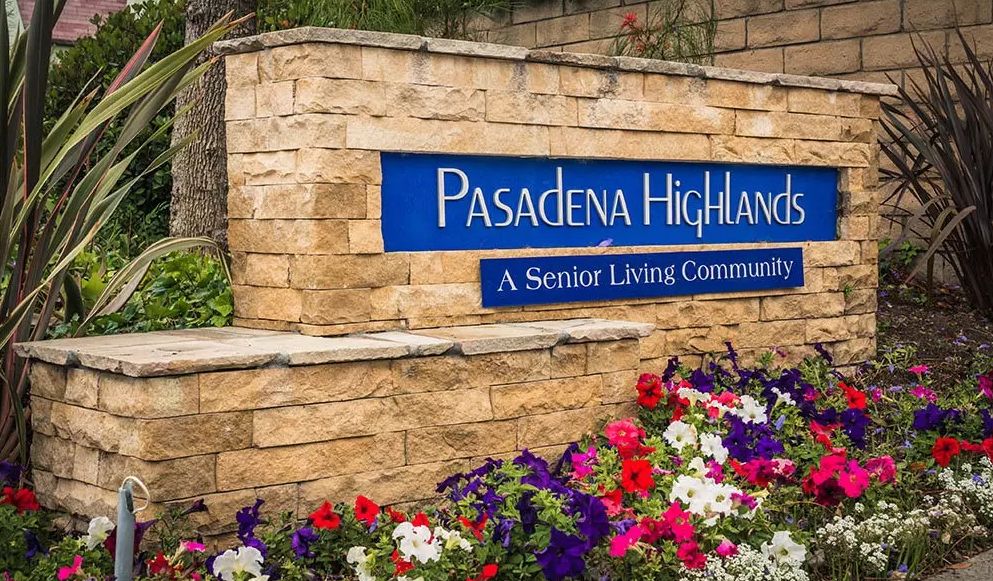 Entrance sign for Pasadena Highlands, a senior living community, surrounded by colorful flowers.