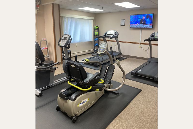 A fitness room with various exercise equipment, including treadmills and a stationary bike.