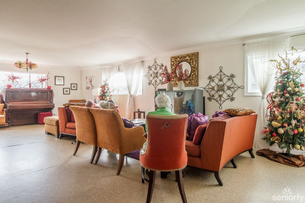 A cozy living room with orange and red chairs arranged around a television, featuring decorative elements on the walls.