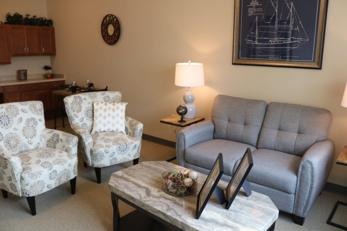 A cozy living room with a gray sofa, patterned armchairs, and a stylish coffee table.