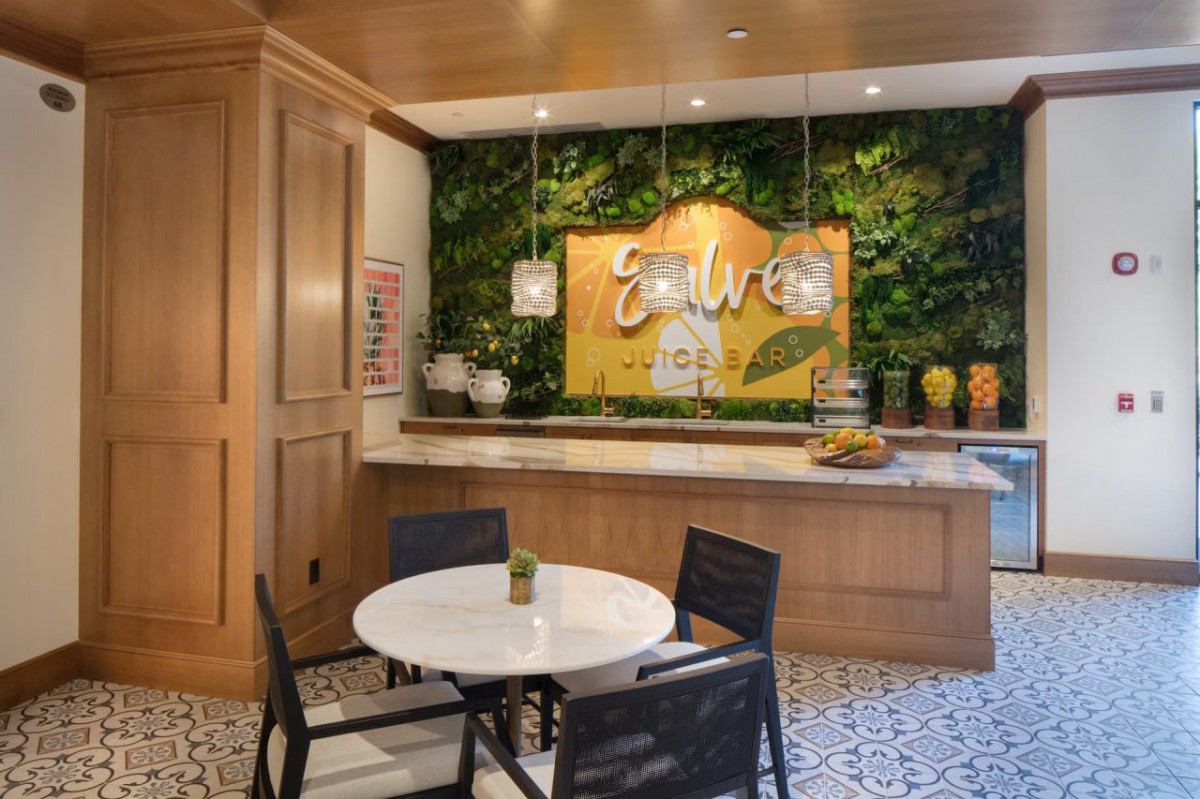 A cozy indoor cafe with a green wall, wooden paneling, and a seating area featuring a round table and chairs.
